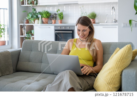 Smiling woman sit on home couch with laptop smiling looking at screen receive good news in message. 121678715