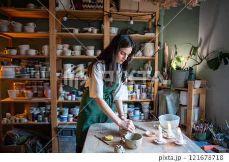 Woman learning how to make hand-formed tableware during pottery masterclass. Art therapy.  121678718
