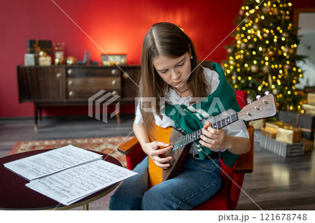 Diligent woman musician sharpens balalaika skills with notes, preparing for Christmas concert 121678748