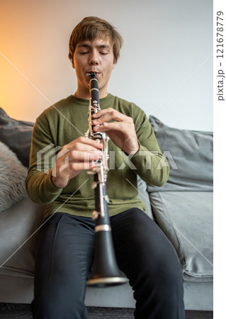 Clarinet player. Clarinetist playing flute woodwind music instrument at home. Guy plays oboe 121678779
