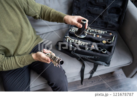 Hand of musician dismantle clarinet, arrange parts neatly in case post performance. Careful handling 121678787