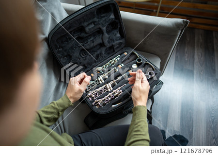 Hands of musician dismantle clarinet after practice, hygiene, durability of wind instrument in case 121678796
