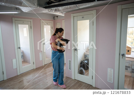 Female worker in animal hotel walks cat, organizing stroll in turns for feline interaction, comfort Female worker in animal hotel walks cat, organizing stroll in turns for feline interaction, comfort 121678833