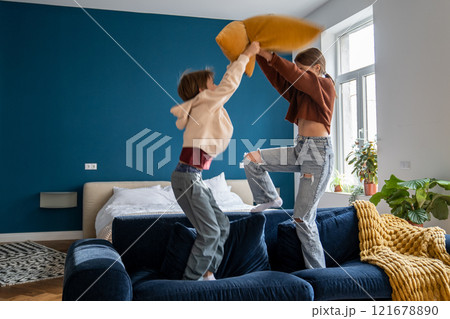 Naughty siblings boy and girl staged pillow fight on couch at home. Fun playing active game together 121678890