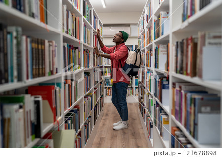 Thoughtful African American student man in glasses choosing book in college library or bookstore Thoughtful African American student man in glasses choosing book in college library or bookstore 121678898