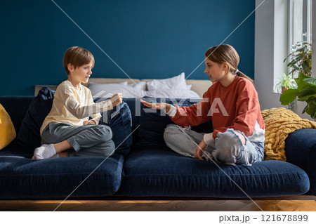 Two kids boy and girl friends play rock paper scissors while sitting on sofa at home 121678899