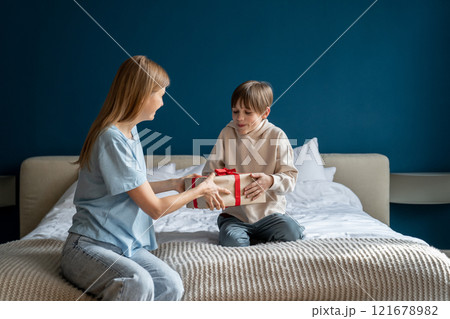 Excited overjoyed little boy child receiving unexpected birthday gift from mother at home Excited overjoyed little boy child receiving unexpected birthday gift from mother at home 121678982