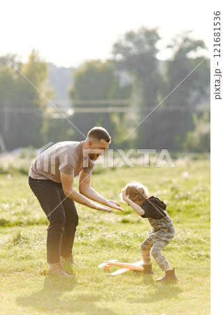Single caucasian dad and child boy play and laugh together. Father looking toy plane and having fun on summer park outdoor. Curly toddler boy has an eyeglasses. Single caucasian dad and child boy play and laugh together. Father looking toy plane and having fun on summer park outdoor. Curly toddler boy has an eyeglasses. 121681536