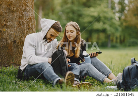 Tourists in a summer forest. Girl in a black t-shirt. Man use a phone. 121681649