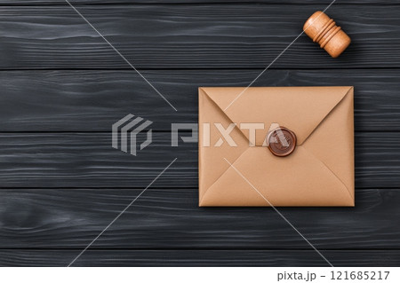 Elegant envelope with wax seal and wooden stamp on dark wooden table Elegant envelope with wax seal and wooden stamp on dark wooden table 121685217