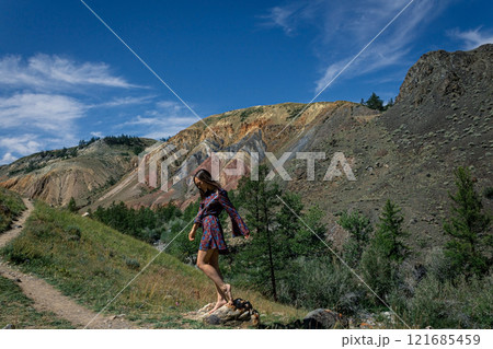 a young woman in short dress stands next to hiking trail against the backdrop of famous landmark Altai Mars in canyon a young woman in short dress stands next to hiking trail against the backdrop of famous landmark Altai Mars in canyon 121685459