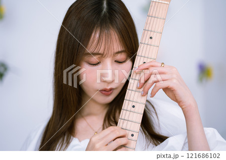 エレキギターを持つロングヘアの若い女性 121686102