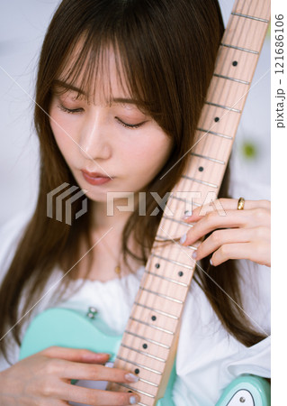 エレキギターを持つロングヘアの若い女性 121686106