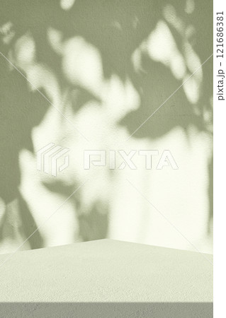 Empty table with Leaves Shadow on Light Green Wall in Vertical Background Empty table with Leaves Shadow on Light Green Wall in Vertical Background 121686381