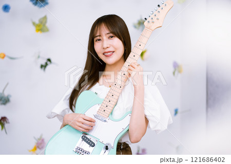 エレキギターを持つロングヘアの若い女性 121686402