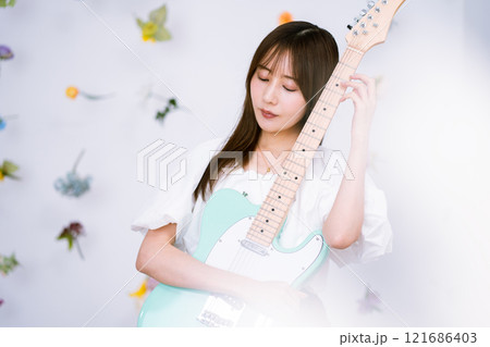 エレキギターを持つロングヘアの若い女性 121686403