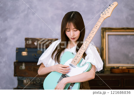 エレキギターを持つロングヘアの若い女性 121686836