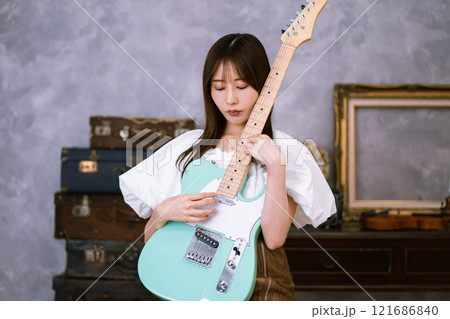 エレキギターを持つロングヘアの若い女性 121686840