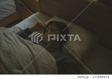 ベッドで苦しそうに眠る若い女性 121686958