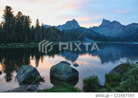 Twilight on Shore of large mountain lake, surrounded by coniferous forest, peak 121687503