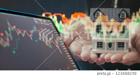 Real estate investment concept with trading chart and miniature house in hands overlaid with market trends 121688230