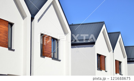 Terraced family homes in newly developed housing estate. The real estate market in the suburbs. New single family houses in a new development area. Residential homes with modern facade.  121688675