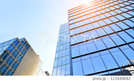 Looking up at the commercial buildings in downtown. Modern office building against blue sky. Windows of a modern glass building. 121688682