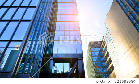 Looking up at the commercial buildings in downtown. Modern office building against blue sky. Windows of a modern glass building. Looking up at the commercial buildings in downtown. Modern office building against blue sky. Windows of a modern glass building. 121688684
