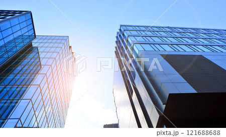 Looking up at the commercial buildings in downtown. Modern office building against blue sky. Windows of a modern glass building. Looking up at the commercial buildings in downtown. Modern office building against blue sky. Windows of a modern glass building. 121688688