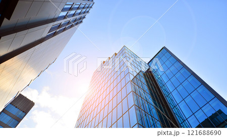 Looking up at the commercial buildings in downtown. Modern office building against blue sky. Windows of a modern glass building. 121688690