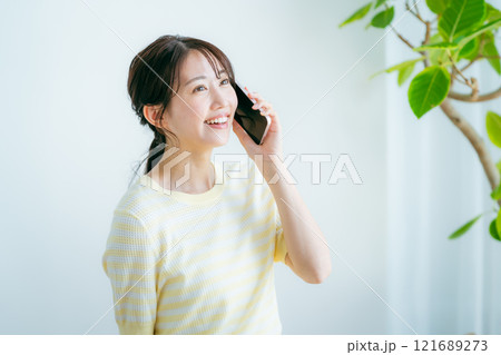 部屋でスマホを操作する女性 部屋でスマホを操作する女性 121689273