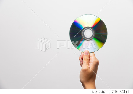 Hand holding CD or DVD disc against light on white background. Data erasure, old digital media, rarity 121692351