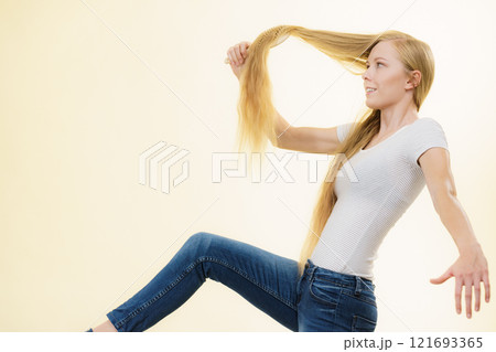 Blonde girl brushing her long hair 121693365