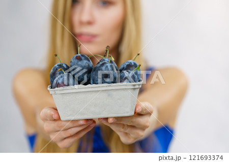 Girl holds plum fruits 121693374