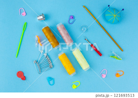 Sewing accessories on a blue bed background. 121693513