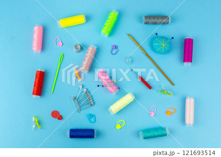 Sewing accessories on a blue bed background. 121693514