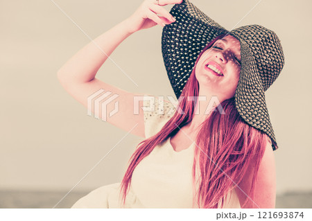 Redhaired happy girl in black hat on beach. Redhaired happy girl in black hat on beach. 121693874