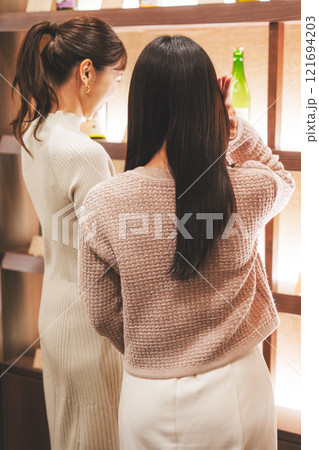 日本酒を選ぶ若い女性　【撮影協力・新潟地酒 premium SAKE 蔵KURA】 121694203