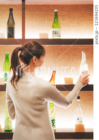 日本酒を選ぶ若い女性　【撮影協力・新潟地酒 premium SAKE 蔵KURA】 121694205
