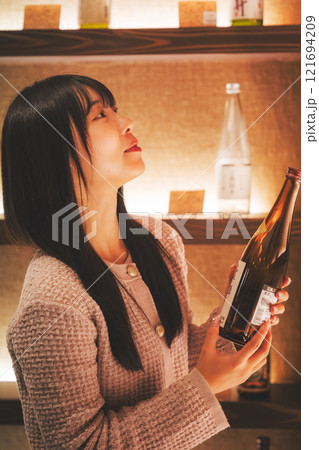 日本酒を選ぶ若い女性　【撮影協力・新潟地酒 premium SAKE 蔵KURA】 121694209