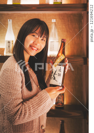 日本酒を選ぶ若い女性　【撮影協力・新潟地酒 premium SAKE 蔵KURA】 121694212