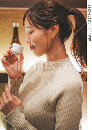 日本酒を試飲する若い女性【撮影協力・新潟地酒 premium SAKE 蔵KURA】 日本酒を試飲する若い女性【撮影協力・新潟地酒 premium SAKE 蔵KURA】 121694218