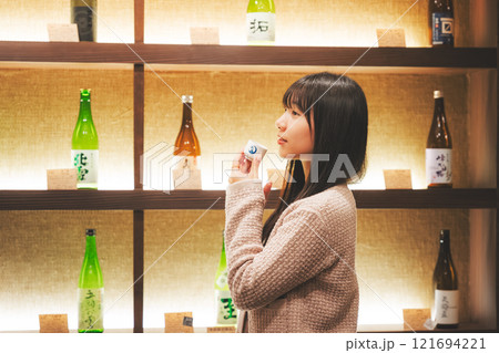 日本酒を試飲する若い女性【撮影協力・新潟地酒 premium SAKE 蔵KURA】 日本酒を試飲する若い女性【撮影協力・新潟地酒 premium SAKE 蔵KURA】 121694221