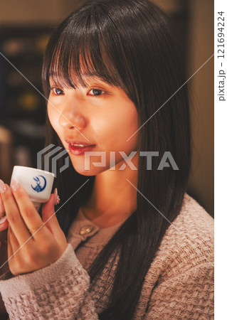 日本酒を試飲する若い女性【撮影協力・新潟地酒 premium SAKE 蔵KURA】 日本酒を試飲する若い女性【撮影協力・新潟地酒 premium SAKE 蔵KURA】 121694224