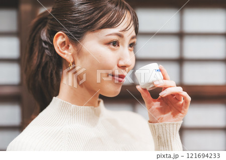 日本酒を試飲する若い女性【撮影協力・新潟地酒 premium SAKE 蔵KURA】 日本酒を試飲する若い女性【撮影協力・新潟地酒 premium SAKE 蔵KURA】 121694233