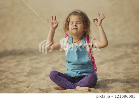 child doing yoga on the beach in Denmark 121696083
