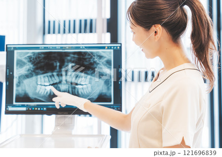 レントゲン写真で歯の状態を説明をする若い女性 レントゲン写真で歯の状態を説明をする若い女性 121696839