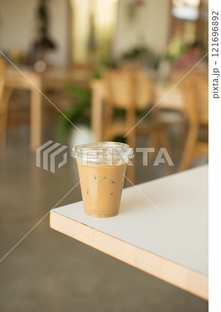 A refreshing iced coffee sits on a table in a cozy cafe. A refreshing iced coffee sits on a table in a cozy cafe. 121696892