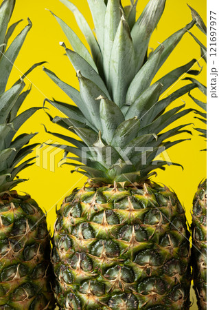 Ripe fresh pineapples on a yellow background close-up. Ripe fresh pineapples on a yellow background close-up. 121697977