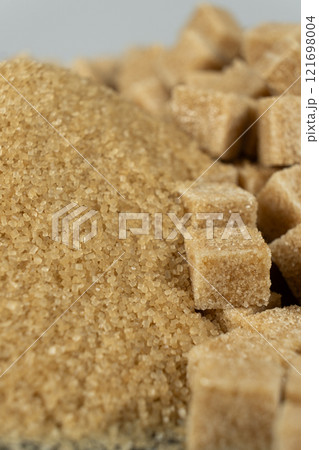 Brown cane unrefined demerara sugar in the form of crystals and cubes Brown cane unrefined demerara sugar in the form of crystals and cubes 121698004